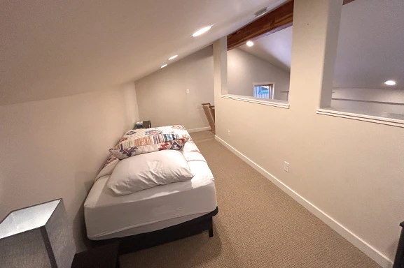 A small room with a bed, carpet, and mirrors.