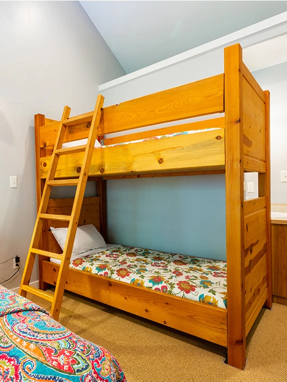 A bunk bed with a ladder and floral sheets